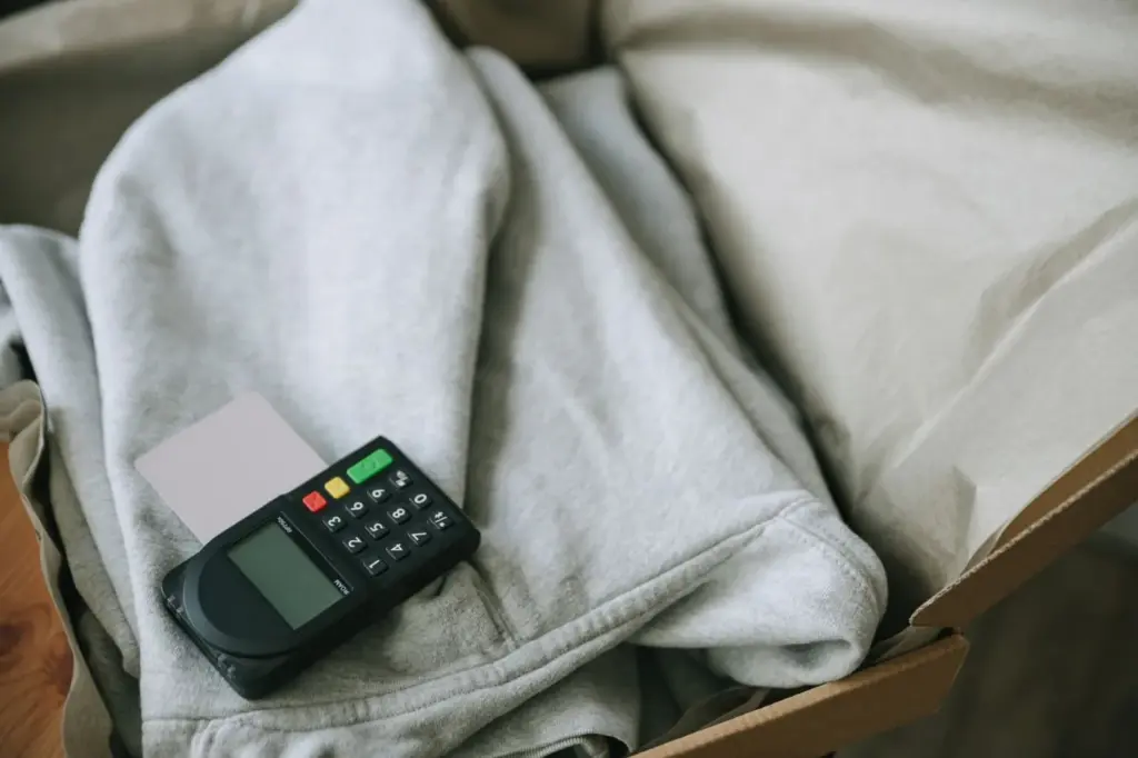A card payment terminal resting on folded clothing in a small shop